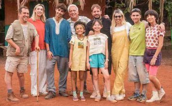 Foto de grupo de los actores principales de la película 'La familia Benetón +2' posando sonrientes en un exterior de tierra roja y una construcción rústica. De izquierda a derecha aparecen El Langui, Anabel Alonso, Alí Dia, Leo Harlem, Kamsiyochi Ngene, Joaquín Mazón (director), Gala Bichir, Diego Montejo, Meilin Chen.